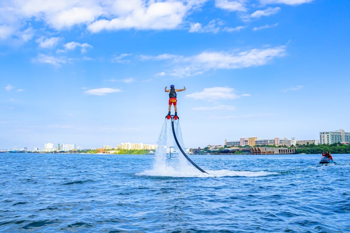 a man flying through the air on a boat in a body of water